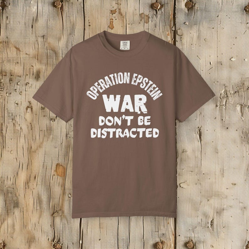 Anti War with Iran Operation Epstein Don't be Distracted. This garment speaks with conviction. A heavyweight, garment-dyed tee printed with a bold, protest-forward message that draws attention without shouting. The soft, broken-in hand of garment dyeing and the relaxed fit make it comfortable for long days at rallies, vigils, or standing on the street holding a sign. Worn by someone who wants their stance to be seen and felt, it layers easily under a jacket or stands alone as a statement piece.