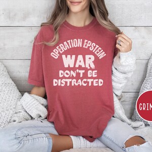 Anti War with Iran Operation Epstein Don't be Distracted. This garment speaks with conviction. A heavyweight, garment-dyed tee printed with a bold, protest-forward message that draws attention without shouting. The soft, broken-in hand of garment dyeing and the relaxed fit make it comfortable for long days at rallies, vigils, or standing on the street holding a sign. Worn by someone who wants their stance to be seen and felt, it layers easily under a jacket or stands alone as a statement piece.