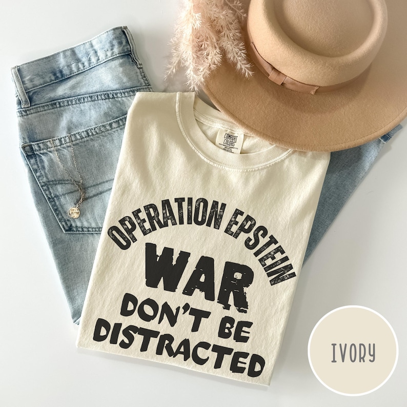 Anti War with Iran Operation Epstein Don't be Distracted. This garment speaks with conviction. A heavyweight, garment-dyed tee printed with a bold, protest-forward message that draws attention without shouting. The soft, broken-in hand of garment dyeing and the relaxed fit make it comfortable for long days at rallies, vigils, or standing on the street holding a sign. Worn by someone who wants their stance to be seen and felt, it layers easily under a jacket or stands alone as a statement piece.