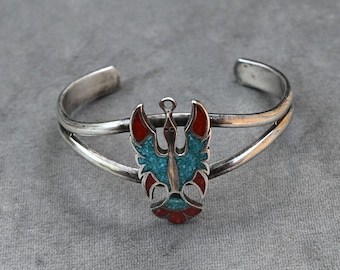 Bracciale rigido Navajo con punzone "GS" raffigurante l'uccello del tuono o la fenice in argento sterling, corallo rosso e turchese blu, lunghezza indossabile 6 7/8 pollici, peso 24,7 grammi.