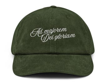 May include: A dark green corduroy baseball cap with the embroidered phrase "Ad majorem Dei gloriam" in white script. The cap has a curved brim and an adjustable strap.