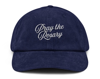 May include: A navy blue corduroy baseball cap with white embroidered text that reads "Pray the Rosary".