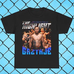 May include: Black t-shirt featuring a graphic of a mixed martial arts fighter. The design includes the text "THE JUSTIN HIGHLIGHT" in silver and "GAETHJE" in blue. The image shows the fighter in the center with other fighters in the background.