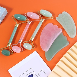 May include: Set of four jade rollers and gua sha tools for facial massage. The tools are made of green and pink jade and have gold accents.
