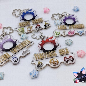 May include: A collection of acrylic keychains with various designs and text. Each keychain features a circular design with a name and symbols. The keychains are in various colors, including blue, purple, and red. Some have a silver-colored chain.