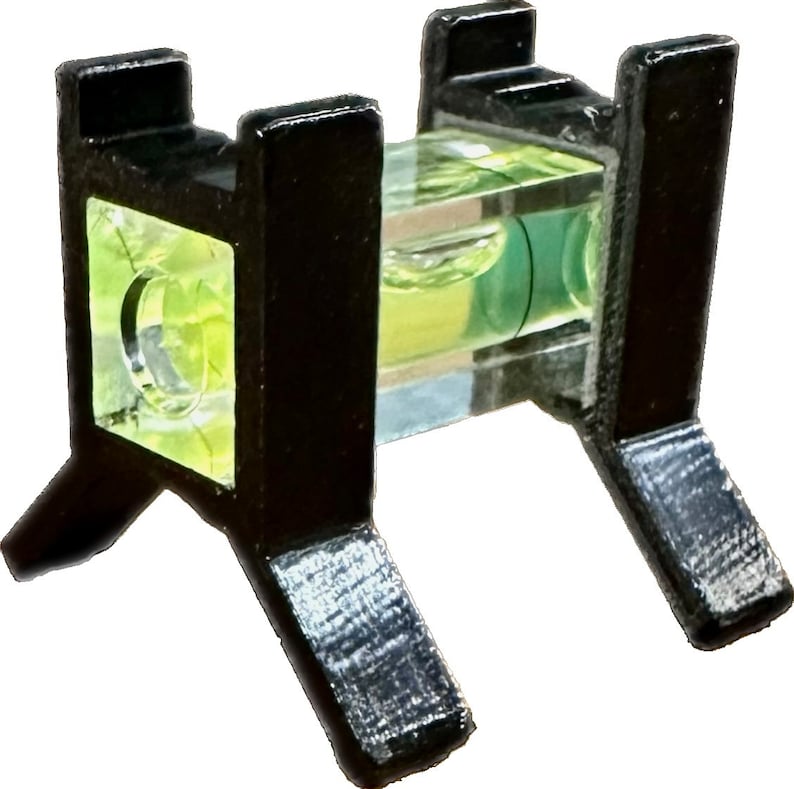 May include: A black plastic level with three legs on each side. The level has a clear glass tube with a green bubble inside.