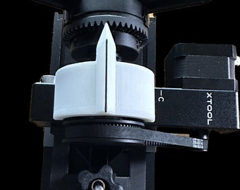May include: A black and white 3D printed tool with a white dial and a black knob. The tool is labeled "XTOOL" and has a black gear system.