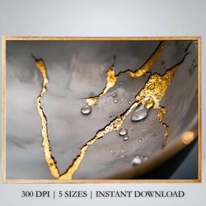 May include: A close-up of a gray and gold textured surface with gold leaf accents and water droplets. The surface is cracked and has a rough texture.