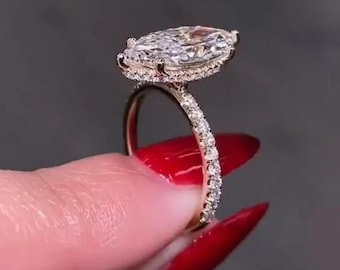 May include: A gold engagement ring with a large, clear marquise-shaped diamond set in a halo of smaller diamonds. The band is also set with smaller diamonds.