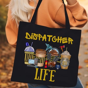 May include: Black tote bag with the text "Dispatcher Life" in yellow. The bag features a graphic of four different coffee drinks with various toppings, including whipped cream, chocolate, and sprinkles. The drinks are surrounded by yellow caution tape and other details.