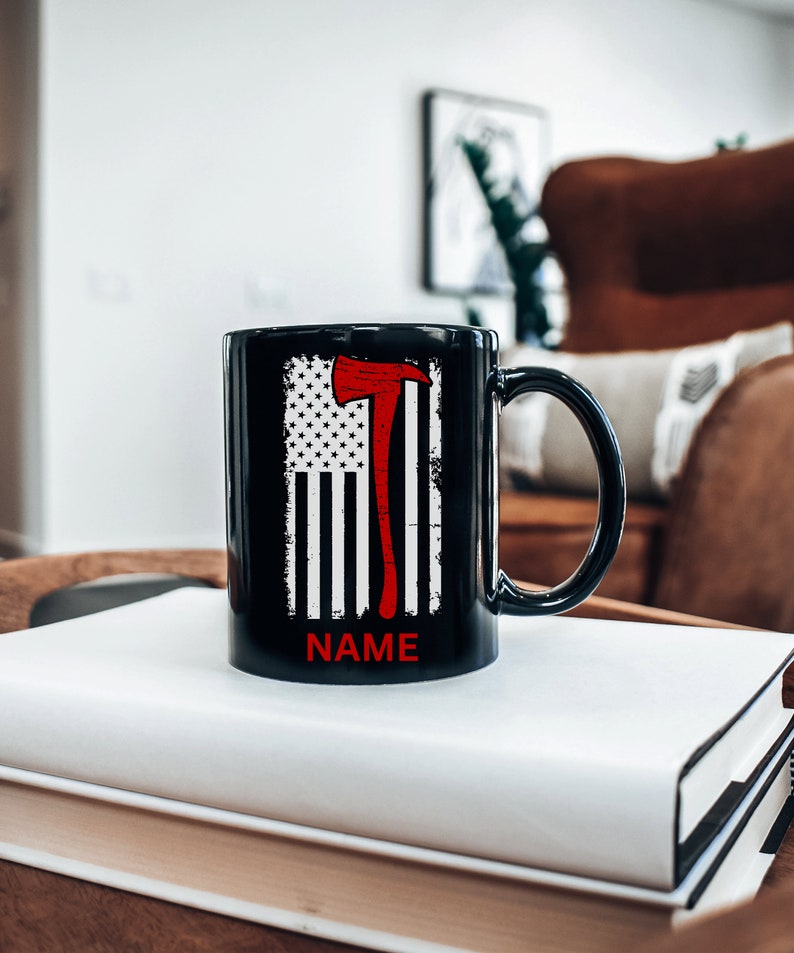 May include: Black ceramic mug featuring a red axe and an American flag design. The text "NAME" is printed on the bottom of the mug.
