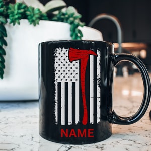 May include: Black coffee mug featuring a white and red American flag design with a red axe. The text "NAME" is printed below the flag.