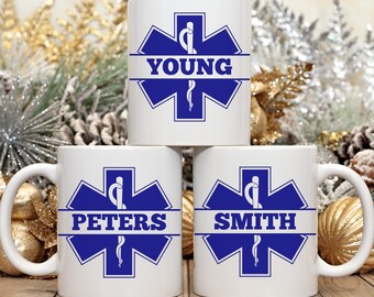 May include: Three white ceramic mugs with blue and white star of life medical symbol designs. The mugs are personalized with the names "YOUNG", "PETERS", and "SMITH".