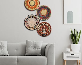 May include: Four woven wall decor baskets with geometric patterns in shades of brown, orange, red, blue, and white. The baskets are hanging on a white wall.