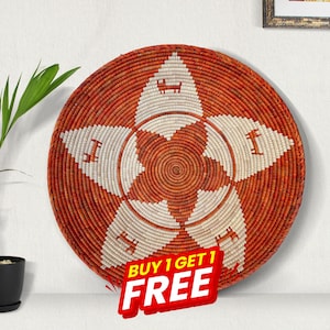 May include: A round, woven basket with a starburst design. The basket is primarily orange with a white star pattern. The text "BUY 1 GET 1 FREE" is in the lower right corner. The basket is likely used for home decor.