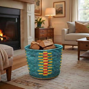 May include: A turquoise woven basket with a yellow and red geometric design, holding logs of firewood. The basket is placed on a rug in front of a fireplace, creating a warm, inviting atmosphere.