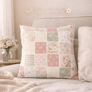 May include: Square patchwork cushion with a floral and gingham pattern in soft pink, cream, and green hues. The cushion is on a bed with a neutral-coloured headboard. The text "soft cozy aesthetic" is at the top.