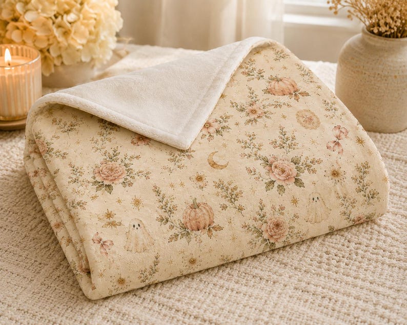 Folded velveteen blanket close-up showing soft plush texture, cream backing, detailed floral ghost pattern, and premium construction.