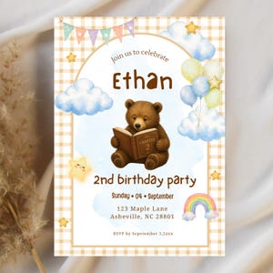 May include: A rectangular birthday invitation card featuring a brown bear reading a book labeled Chapter 2. The design includes a beige gingham border, watercolor clouds, pastel balloons, stars, and a rainbow. Text reads Ethan, 2nd birthday party, Sunday 04 September, 123 Maple Lane, Asheville, NC 28801, and RSVP by September 1, 2xxx.