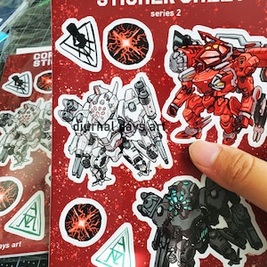May include: A sticker sheet featuring a red, white and black robot design with the text "Core of Armor Sticker Sheet, series 2" and "diurnal days art".