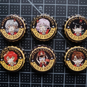 Könnte beinhalten: Sechs schwarze und goldene Flaschenverschlüsse mit einem weißen Stern auf jeder Seite. Jeder Verschluss zeigt einen anderen Anime-Charakter mit einem rot-weißen Design und dem Text "Astral Express Cold Brew".