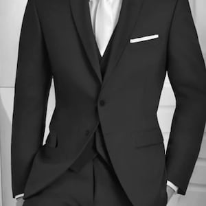 May include: A black suit with a white shirt and tie. The suit has a single button closure and a pocket square.