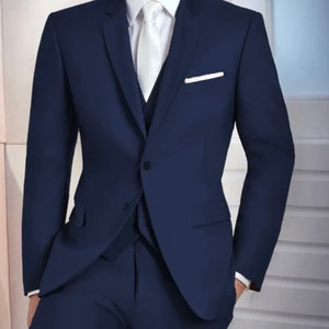 May include: A navy blue suit with a white shirt and tie. The suit has a single button closure and a pocket square.