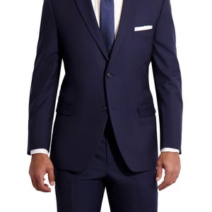 May include: A navy blue suit jacket with a white shirt and a dark blue tie. The jacket has a single button closure and a pocket on the left side.