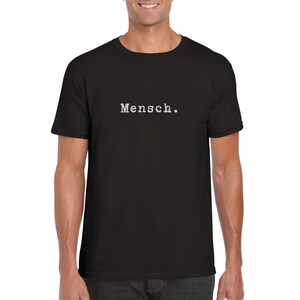 Puede incluir: Una camiseta negra con la palabra "Mensch." impresa en blanco en la parte delantera.