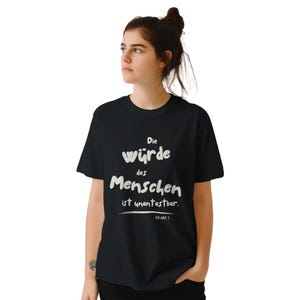 May include: Black t-shirt with white text that reads "Die Würde des Menschen ist unantastbar. GG Art. 1."