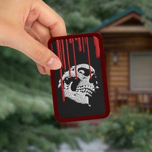 May include: Red embroidered patch with a white skull and dripping blood. The skull has three eyes.