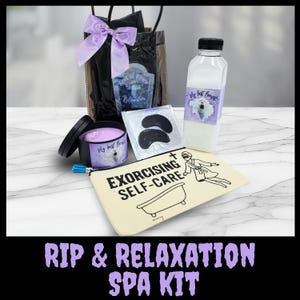 May include: A spa kit with a black gift bag tied with a purple bow, a candle, a bottle, eye masks, and a canvas pouch. The pouch reads "Exorcising Self-Care". The kit includes the text "Rest in Peace & Relaxation" and "My best Boy".