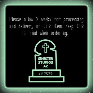 May include: A green neon sign with a tombstone graphic and the text "Please allow 2 weeks for processing and delivery of this item. Keep this in mind when ordering."  The tombstone has a cross on top and the text "SINISTER STUDIOS AZ Est 2023" on the front.