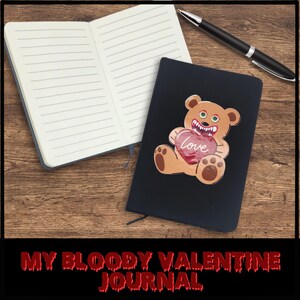 May include: A black journal with the words "My Bloody Valentine Journal" printed on the front. The journal has a graphic of a cartoon bear holding a heart that says "Love" on it.