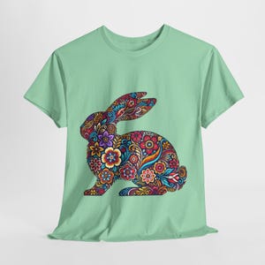 Peut inclure: Un t-shirt vert clair avec un motif de lapin floral coloré.