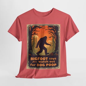 May include: A red t-shirt with a vintage-style graphic of Bigfoot walking through a forest. The graphic says "Bigfoot says watch out for dog poop".