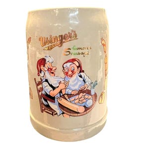 May include: A beige ceramic beer stein with a cartoon image of two elves making sausage. The stein has the text "Usinger's Famous Sausage" on the front.