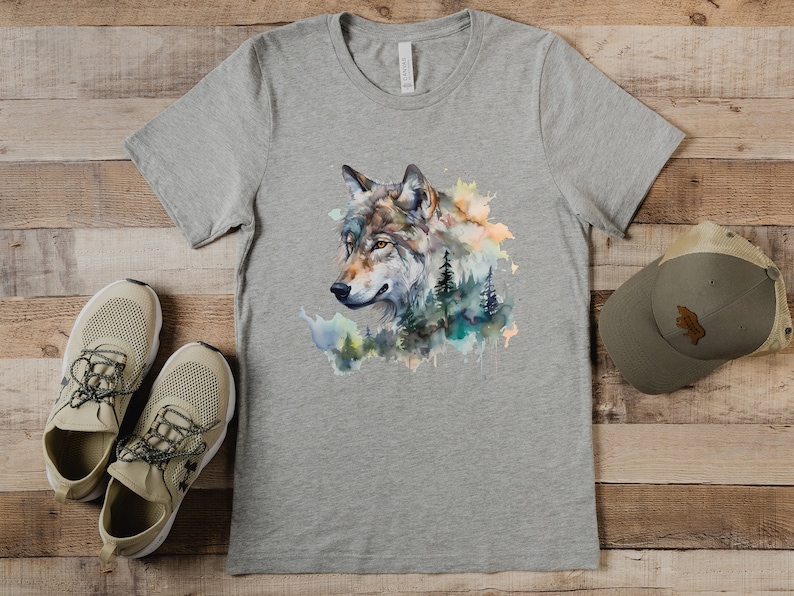 May include: A gray t-shirt with a watercolor design of a wolf's head with a forest background.