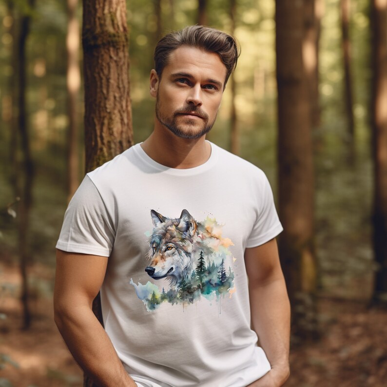 May include: A white t-shirt with a watercolor design of a wolf's head in a forest setting. The wolf is gray and brown with a white chest and a black nose. The forest is green and blue with a yellow sky.