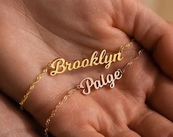 May include: Two gold necklaces with the names "Brooklyn" and "Paige" written in cursive.