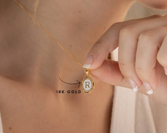 May include: A gold chain necklace with a white oval pendant featuring the letter "R" in gold. The pendant is 18k gold.