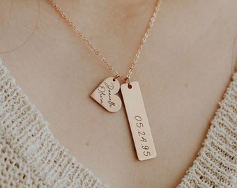 May include: A gold necklace with two charms. The first charm is a heart with the name "Danielle Olivia" engraved on it. The second charm is a rectangular tag with the date "05.24.95" engraved on it.