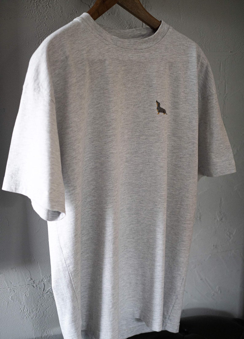 May include: A heather grey t-shirt with a small embroidered dachshund on the front.