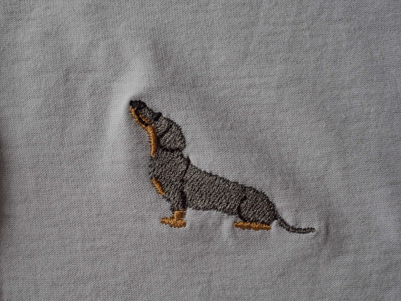 May include: Embroidered dachshund dog design on a white t-shirt.