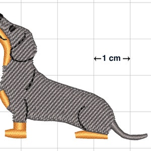 May include: Embroidered design of a gray dachshund dog with orange paws, looking up, on a white grid background with a scale bar indicating 1 cm.