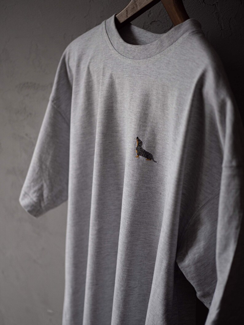 May include: A gray t-shirt with a small embroidered dachshund on the front.