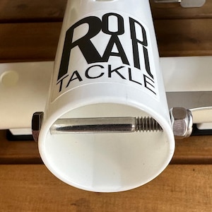 May include: White plastic rod holder with a silver metal screw and nut. The holder has a black logo that says "Rod Rail Tackle".
