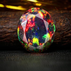 Könnte beinhalten: Ein lebhafter, mehrfarbiger Opal-Edelstein mit facettiertem Schliff. Der Opal zeigt einen Regenbogen an Farben, darunter Rot, Grün, Blau und Gelb.