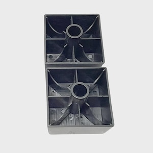 May include: Two black, square furniture feet. Each foot has a central circular opening and internal supports. The feet are made of a durable plastic material and are designed to provide stability and support for furniture.