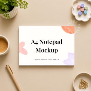 Puede incluir: Maqueta de bloc de notas A4 con texto negro. El bloc de notas es blanco con detalles florales en acuarela en rosa, naranja y morado. La imagen incluye un bolígrafo, una planta pequeña y artículos de papelería sobre una superficie beige.